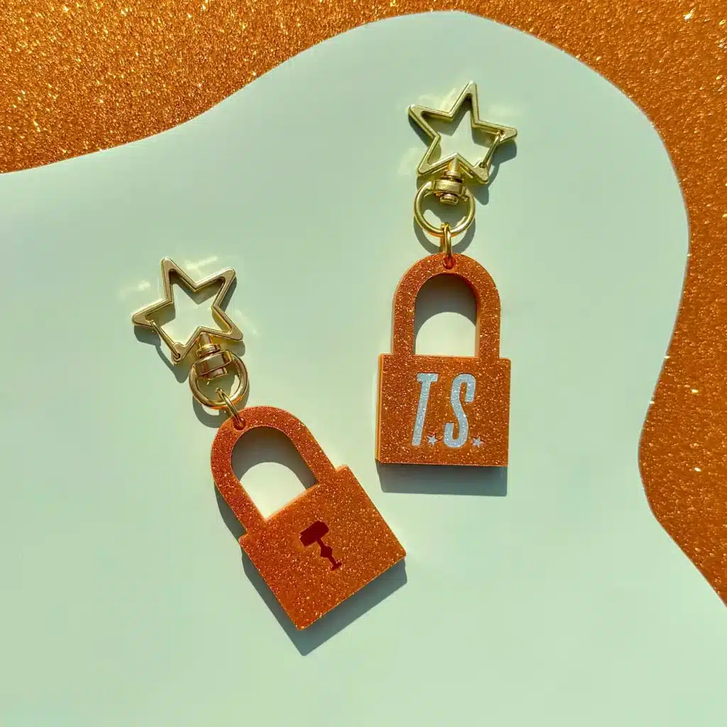 Orange sparkly padlock keyring with green TS logo embedded